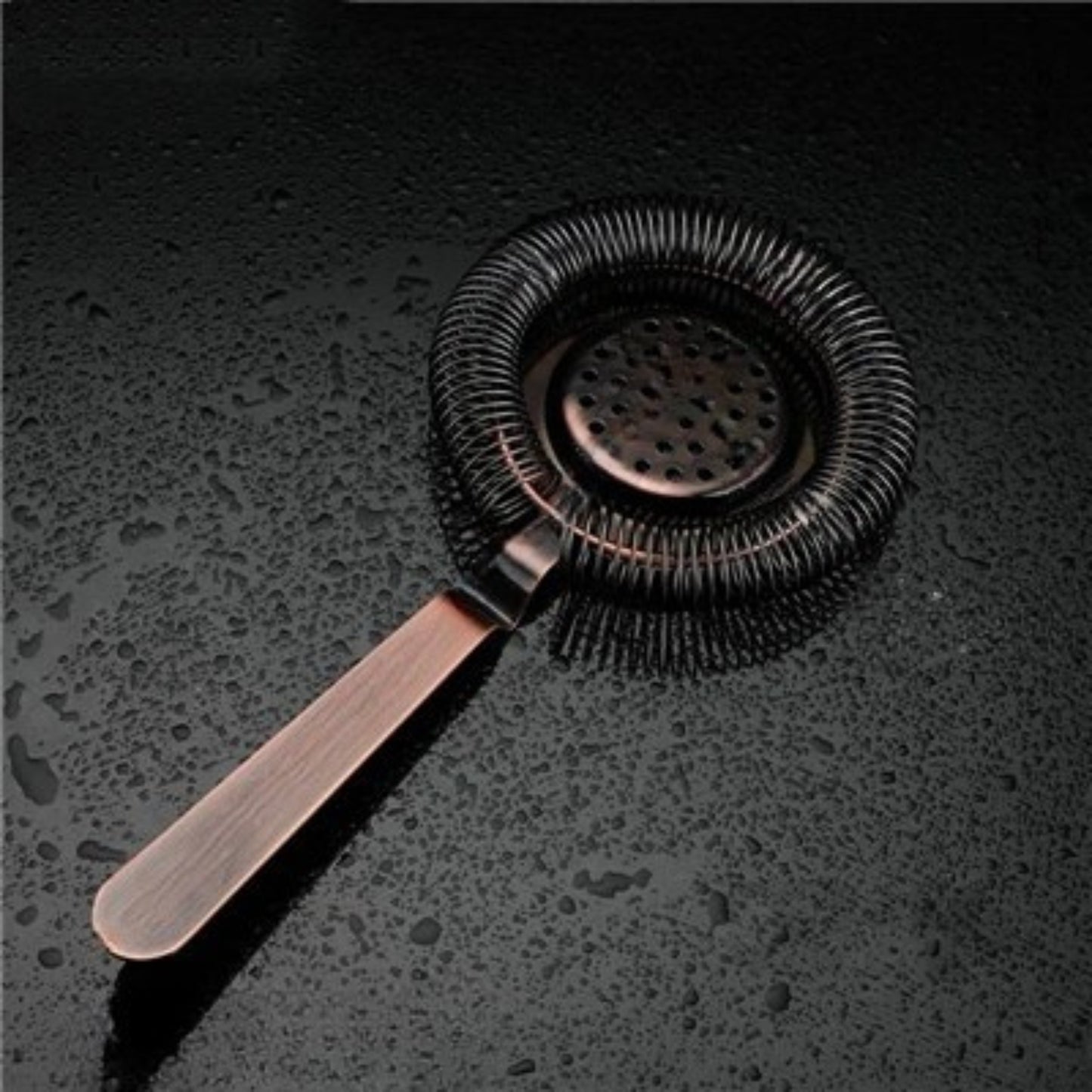 Bronze cocktail strainer on a dark textured surface