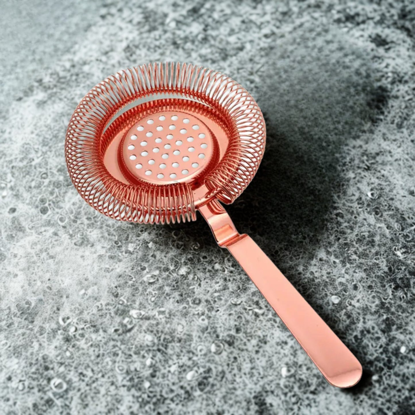 Copper cocktail strainer on a textured gray surface