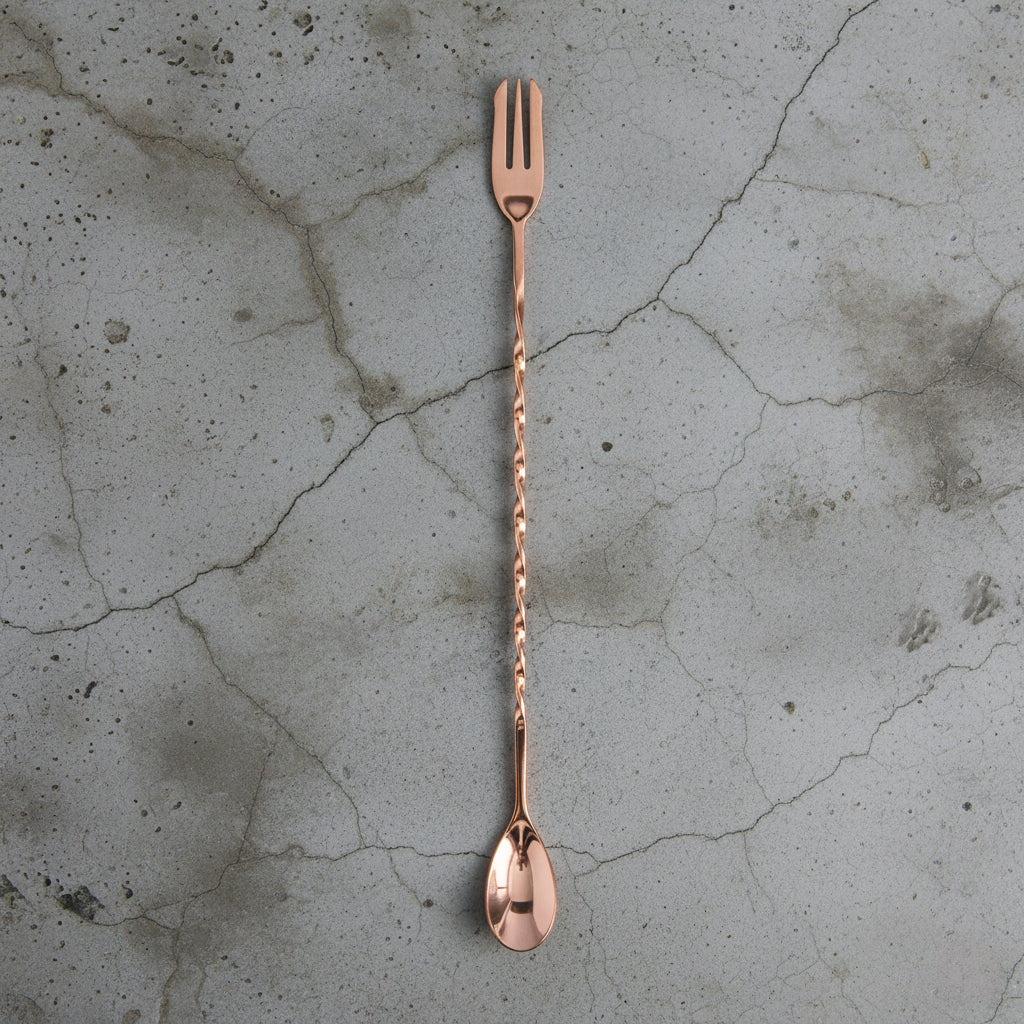 Copper cocktail spoon on a textured concrete surface