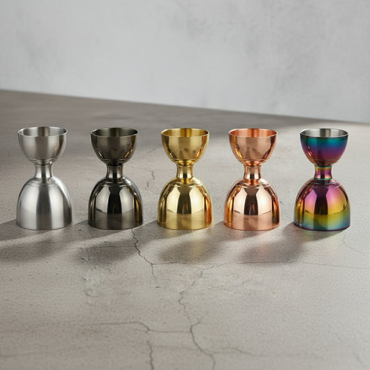 Five metallic jiggers in different colors on a textured surface