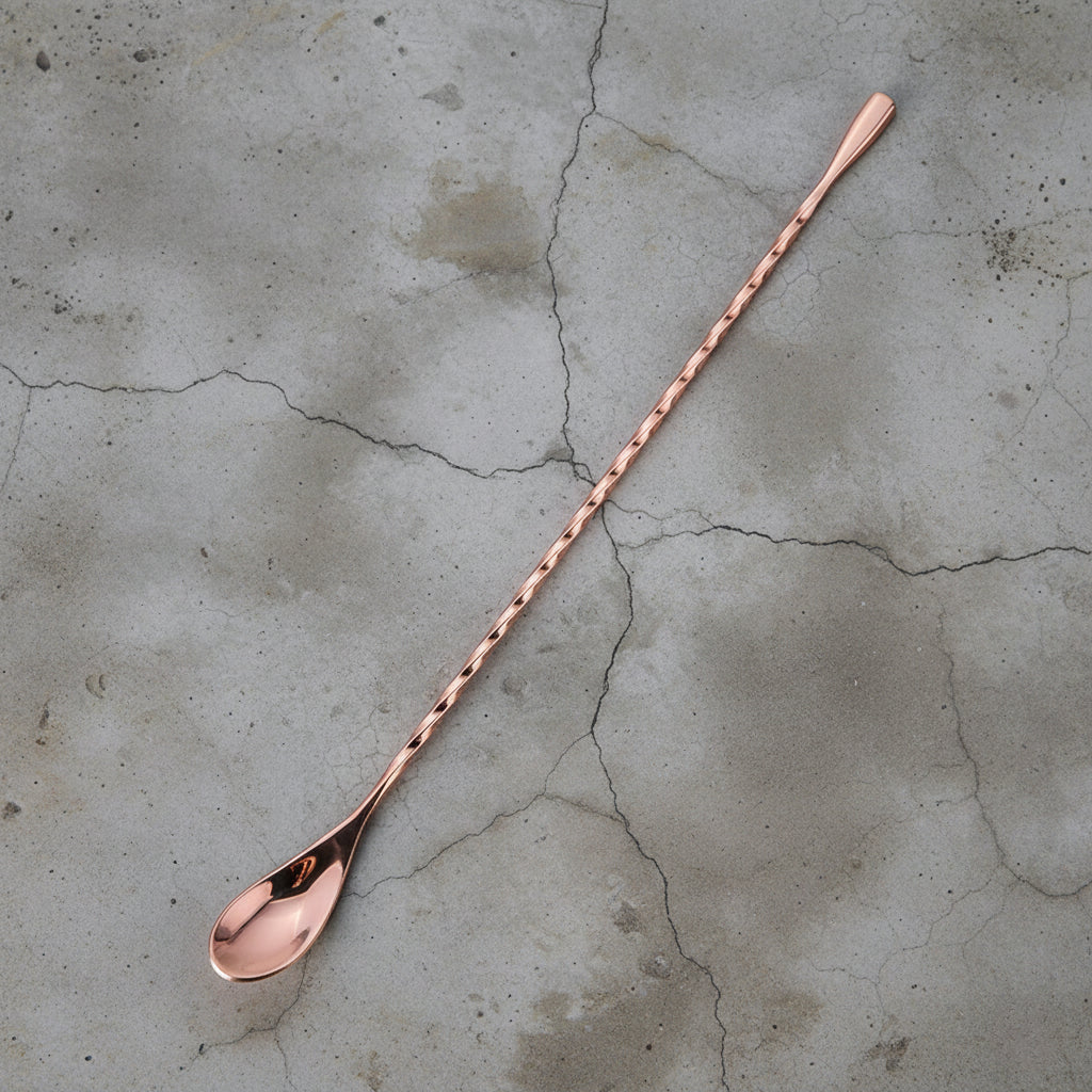 Copper bar spoon on a textured concrete surface
