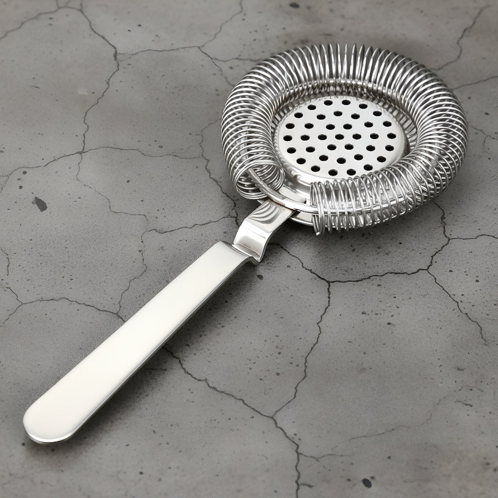Metallic cocktail strainer on a textured gray surface