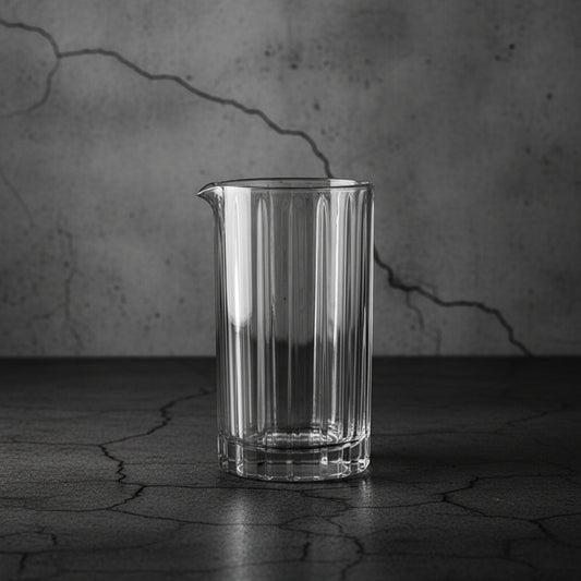 Clear glass pitcher on a textured dark surface with a cracked wall background