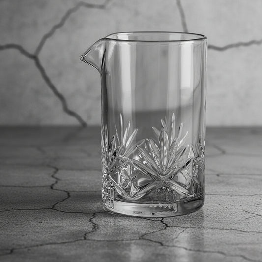 Clear glass pitcher with intricate designs on a textured surface