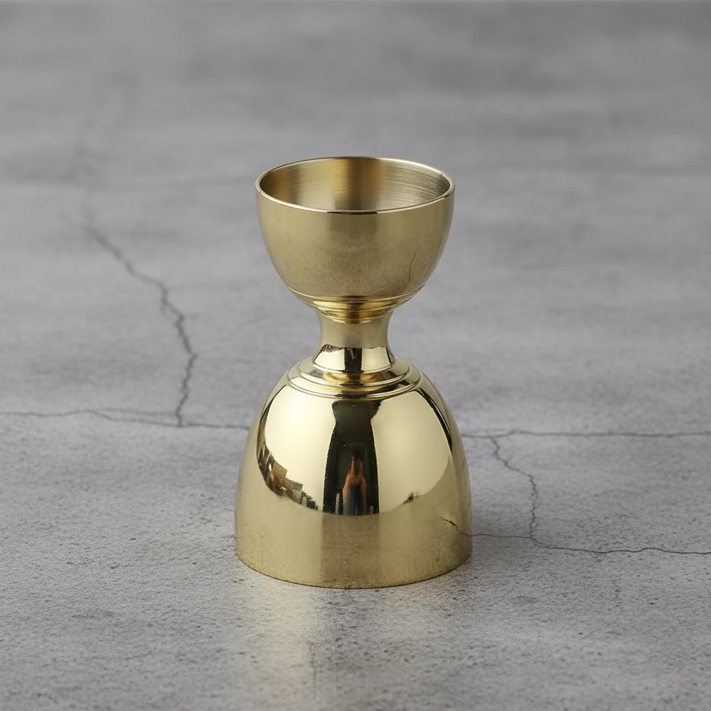 Gold metal drink measuring cup on a gray concrete surface